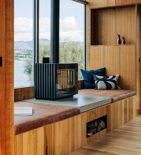 Castworks Hergóm Glance L wood fireplace with sleek black finish and large glass front for modern home heating.